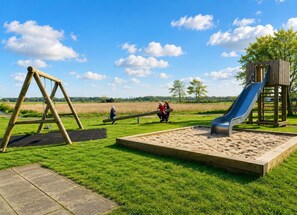 Een speelplaats met een schommel, een glijbaan en een zandbak.