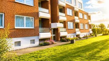 Ein mehrgeschossiges Wohnhaus mit Backsteinfassade, Balkonen und einem gepflegten Rasen.