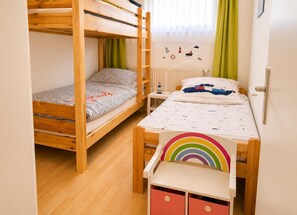 Een kamer met twee stapelbedden, een tafeltje, een stoel en een muur versierd met nautische afbeeldingen.