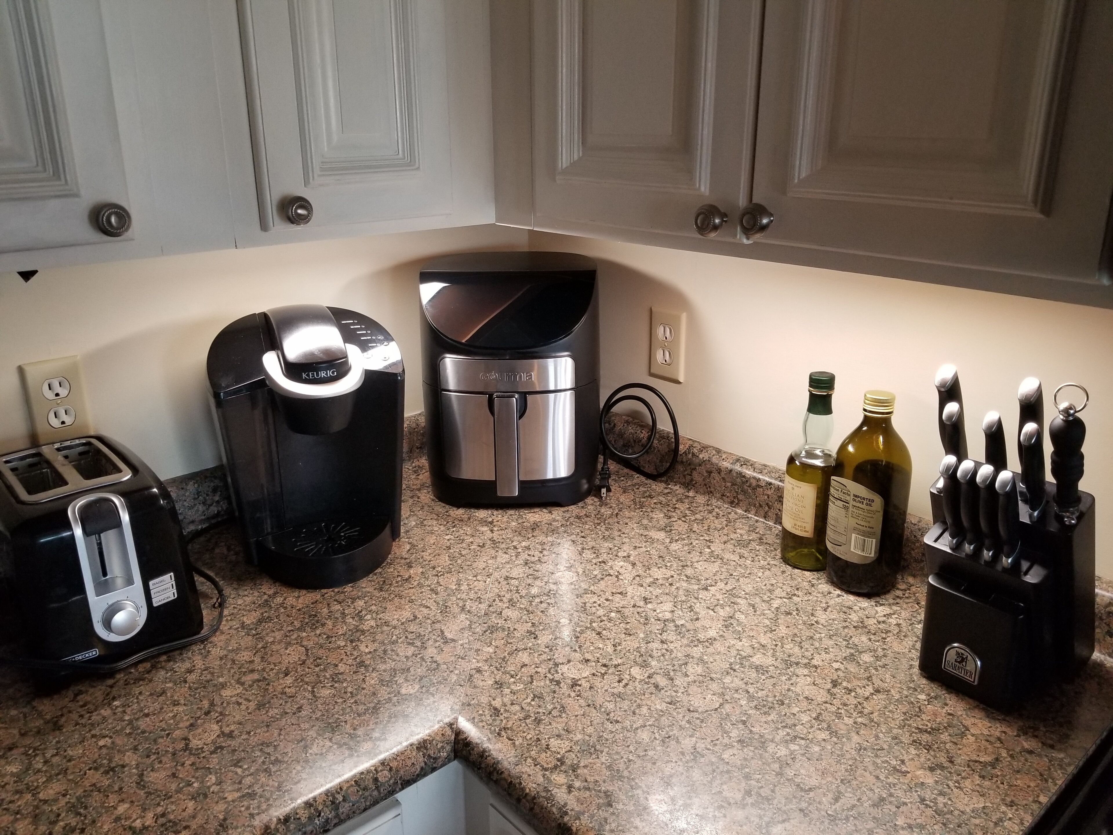 A kitchen with a toaster, coffee maker, and knife block on the counter.