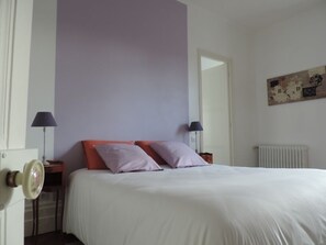 Ein Schlafzimmer mit einem Bett, zwei Nachttischen, einer Lampe und einem Heizkörper.
