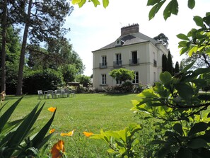 Um edifício grande de dois andares com um gramado e jardim bem cuidados na frente.
