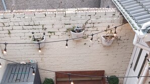 Patio esterno con una panca in legno, un tavolino e piante in vaso.