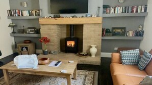 Un soggiorno con camino, scaffali di libri, un divano e una televisione.