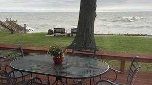 A deck with a metal table and chairs, a potted plant, and a view of the ocean. - Spacious Lakefront Home with Amazing View (Huron)