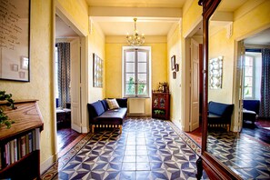 Un couloir avec un sol à motifs, un canapé, un meuble et un miroir.