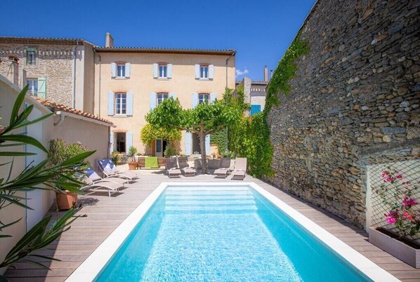 Une piscine avec des chaises longues et un mur en pierre.