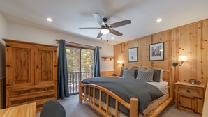 A bedroom with a wooden bed, a ceiling fan, a wooden wardrobe, a desk, and a window with curtains. - Bernese Abode - Fireplace - Newly Updated! (Truckee)