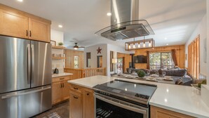 A modern kitchen with stainless steel appliances, wooden cabinets, and a central island. - Bernese Abode - Fireplace - Newly Updated! (Truckee)