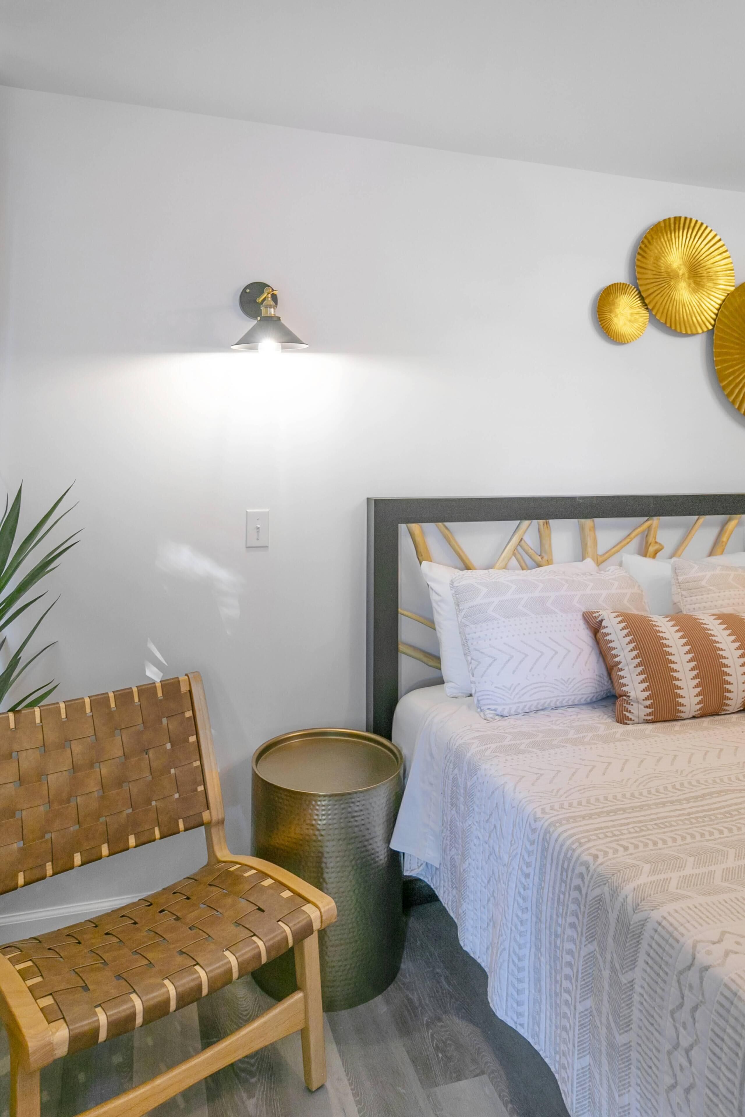 A bedroom with a wooden headboard, a bench, a bedside table, and decorative wall art.