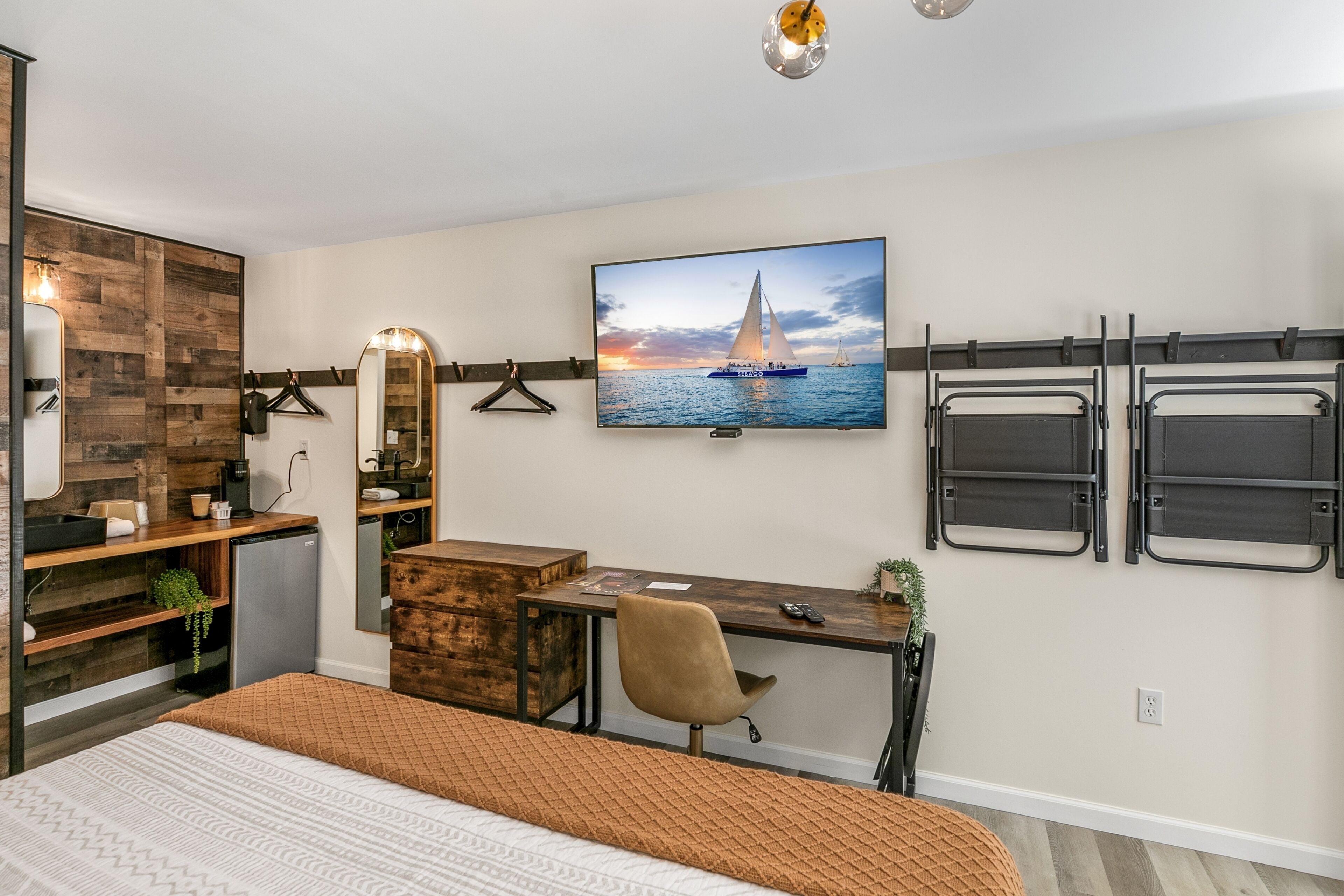 Une chambre moderne comprenant un lit, un bureau, une chaise, une télévision et une armoire.
