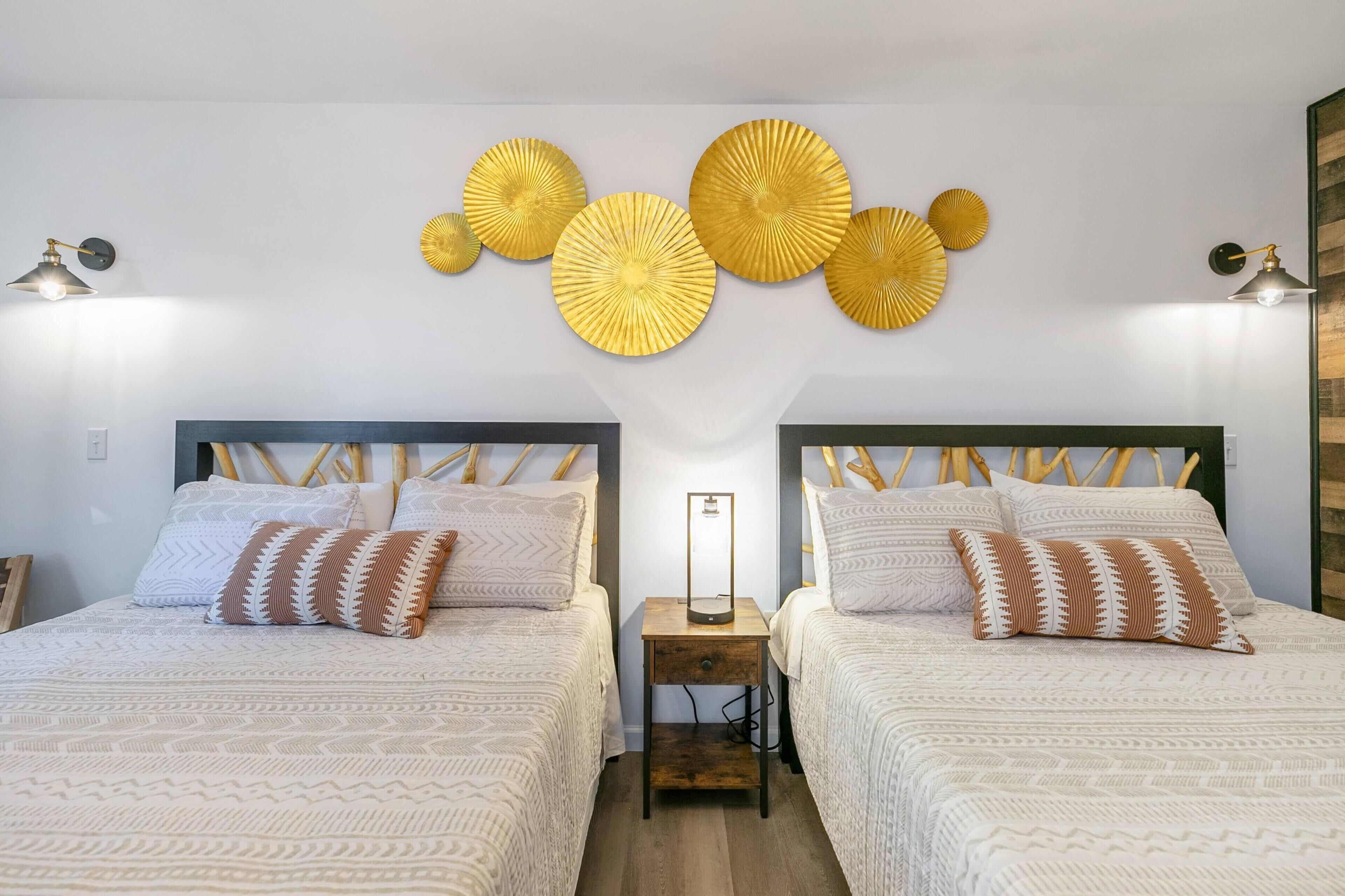 Ein Doppelzimmer mit zwei Nachttischen, einem wandmontierten Spiegel und Wandbildern.