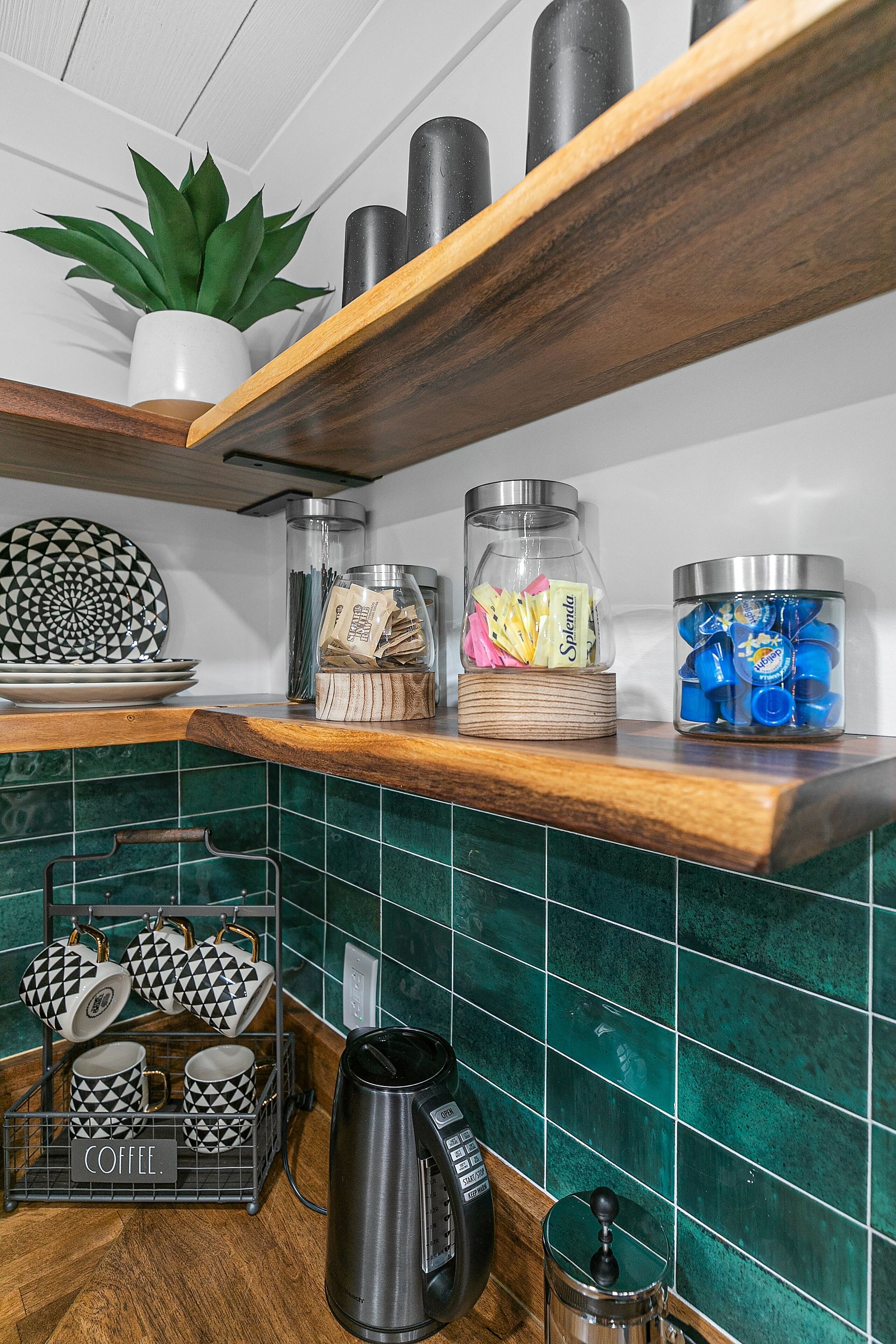 A kitchen with wooden shelves, a coffee maker, and a spice rack.