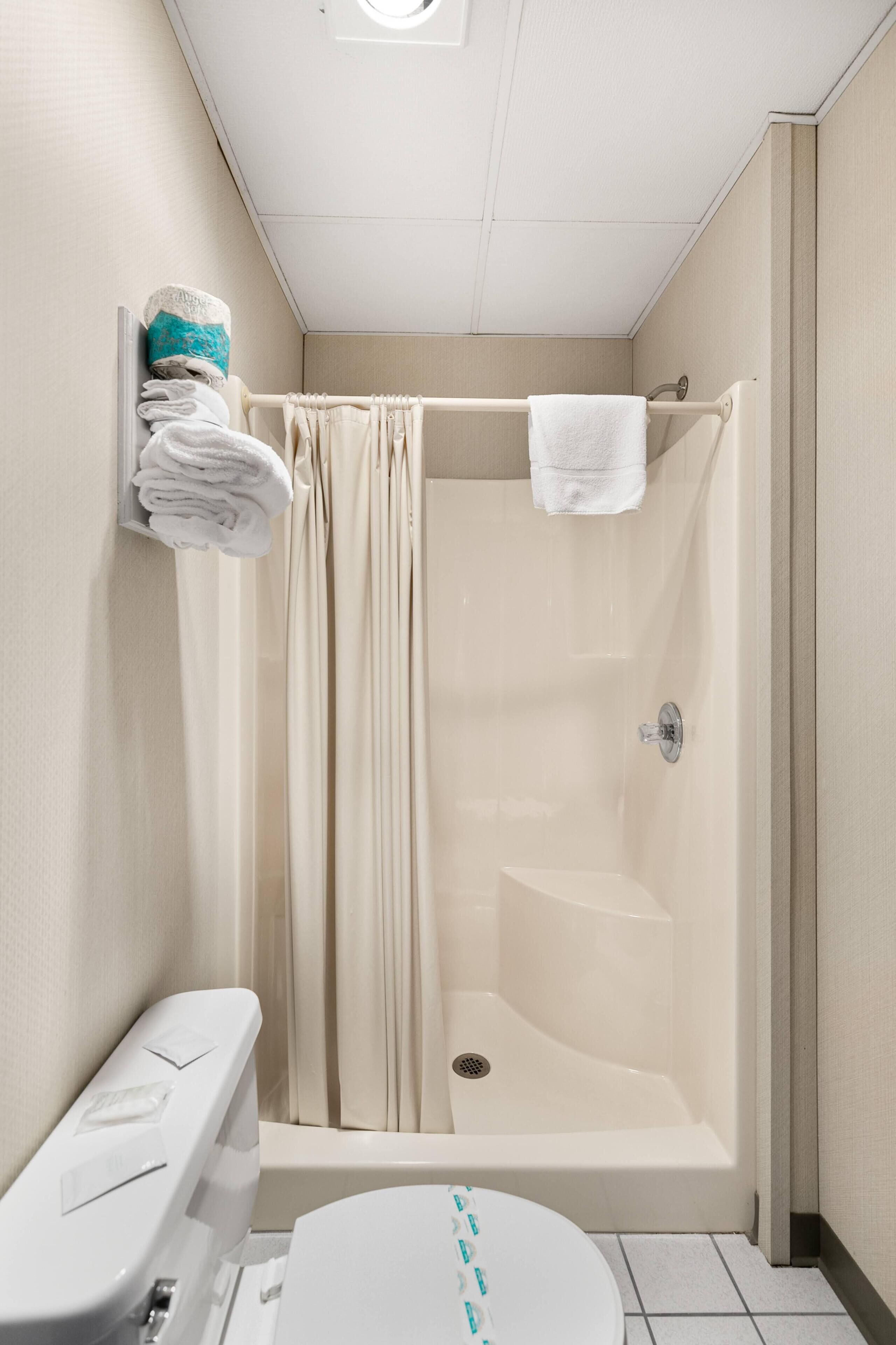 A small, modern bathroom with a shower, toilet, and a towel rack.