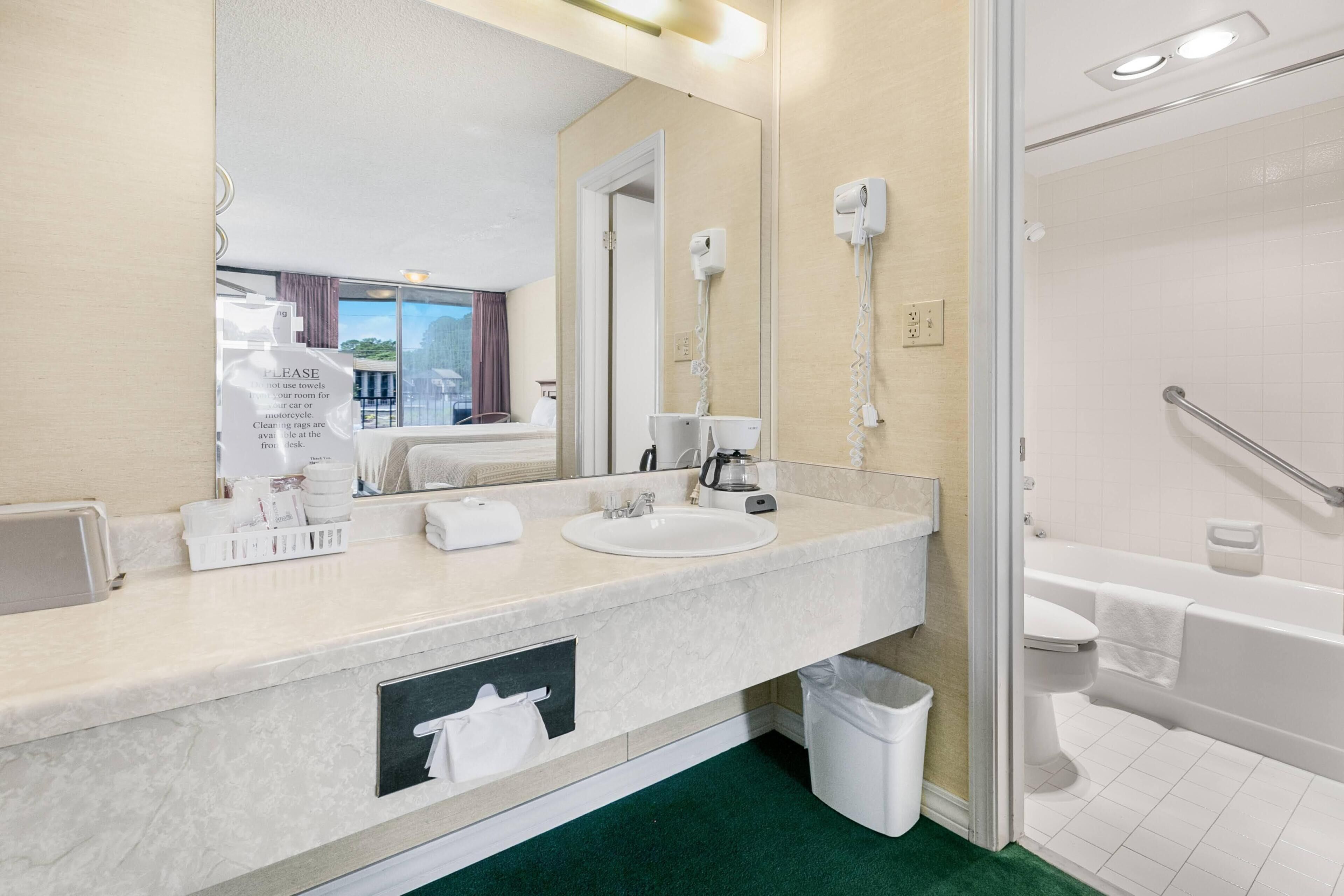 Een moderne badkamer met een grote spiegel, een wastafel, een haardroger en een douche.