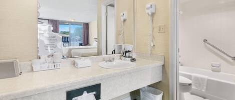 Een moderne badkamer met een grote spiegel, een wastafel, een haardroger en een douche.
