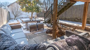 Un patio techado al aire libre con una escalera de madera, un sofá y una mesa de comedor.