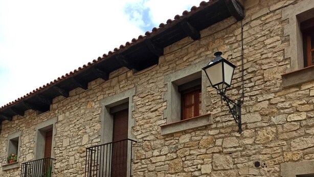 A stone building with multiple windows and balconies, featuring a traditional architectural style.