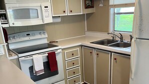 A compact kitchen with a microwave, stove, sink, and cabinets. - Suwannee Riverfront Retreat (Old Town)