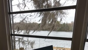 A laptop on a wooden table by a window with a view of a lake and dock. - Suwannee Riverfront Retreat (Old Town)