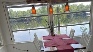 A dining area with a table set for four, white chairs, and hanging pendant lights. - Suwannee Riverfront Retreat (Old Town)
