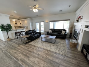 Relax in this inviting living area with a sofa, armchair, and fireplace, offering a view of the outdoors.