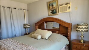 A bedroom with a large bed, a wooden headboard, a nightstand with a lamp, and a wall-mounted air conditioner. - PRIVATE, COMFORTABLE & SPACIOUS! NEAR THE  MARINA, BEACHES & DOWNTOWN! CONDO 302 (San Felípe)