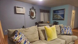 A living room with a beige sofa, a mirror, an air conditioner, and a painting on the wall. - PRIVATE, COMFORTABLE & SPACIOUS! NEAR THE  MARINA, BEACHES & DOWNTOWN! CONDO 302 (San Felípe)