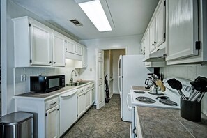 Enjoy cooking in this well-equipped kitchen with a microwave, sink, stove, and kettle.