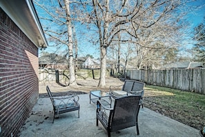 Enjoy outdoor dining or relaxation in this serene patio area with comfortable seating and a small table.