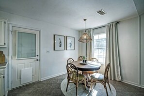 Cozy dining area with a round table and four chairs, pendant light, and framed artworks.