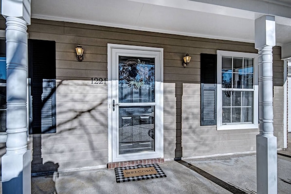 Welcome to 1221, a charming residence with a symmetrical facade and a cozy porch.