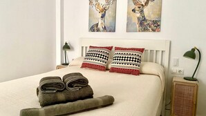 Un letto rifatto con cuscini a fantasia, un asciugamano piegato e una lampada da comodino.