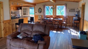 A cozy cabin interior with a dining area, kitchen, and a comfortable seating area with a sofa and chairs. - Comfy St Lawrence getaway for  Fisher or birdwatcher or for a family vacation  (Saint-Anicet)