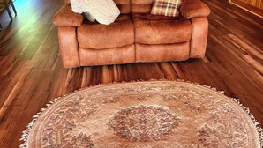 A cozy living room with a brown leather sofa, a patterned rug, and wooden flooring. - Comfy St Lawrence getaway for  Fisher or birdwatcher or for a family vacation  (Saint-Anicet)