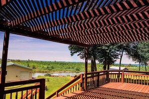 Une terrasse en bois offrant une vue sur un lac et une zone herbeuse.