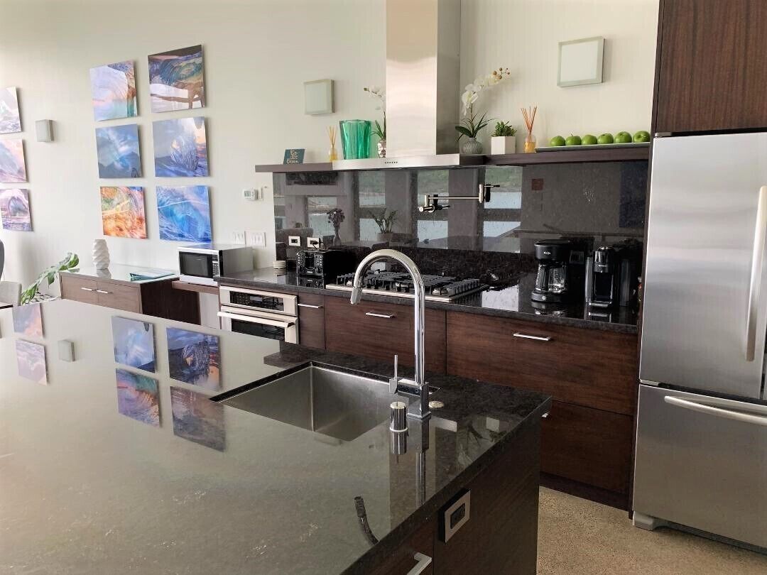 A modern kitchen with a stainless steel refrigerator, a black countertop, and a built-in oven.