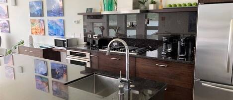 A modern kitchen with a stainless steel refrigerator, a black countertop, and a built-in oven.