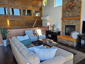 Uma sala de estar moderna com um sofá em formato de L, uma lareira e uma parede de destaque em pedra.