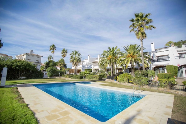 A rectangular swimming pool with a clear blue water, surrounded by a paved deck.