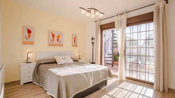 A bedroom with a bed, bedside tables, a nightstand, a ceiling light fixture, and a window with curtains. - BayMar - Alojamientos MarCalm (Mont-roig Bahia)