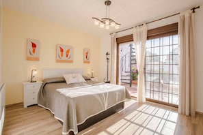 A bedroom with a bed, bedside tables, a nightstand, a ceiling light fixture, and a window with curtains.