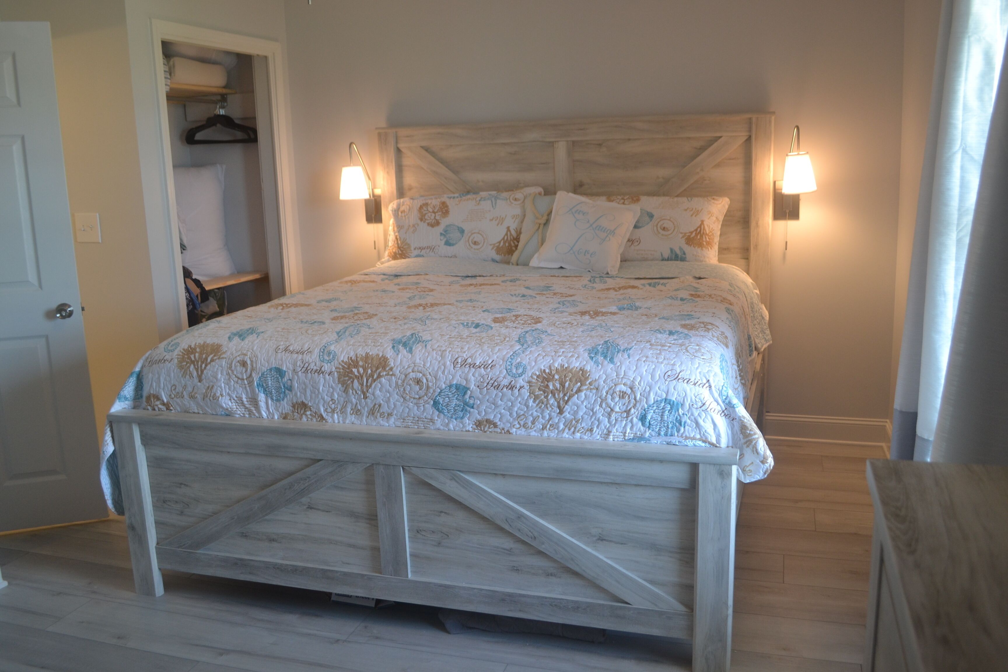 A bedroom with a wooden bed frame, floral bedding, and two wall-mounted lamps.