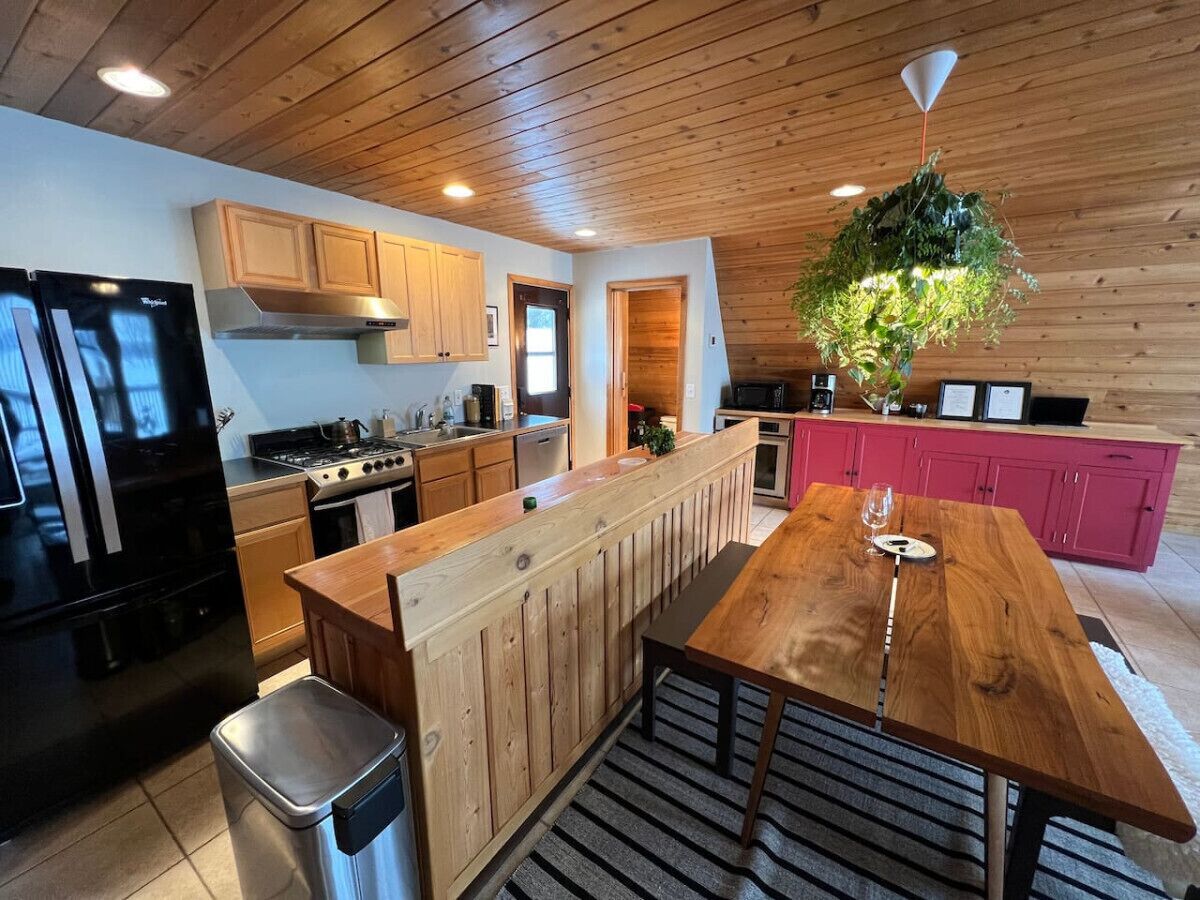 A modern kitchen with wooden cabinetry, a central island, and a dining table.