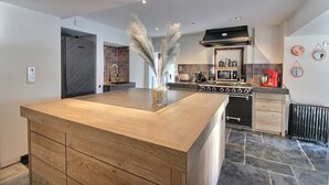 Une cuisine moderne dotée d’un îlot central, d’appareils électroménagers intégrés et d’un dosseret carrelé.