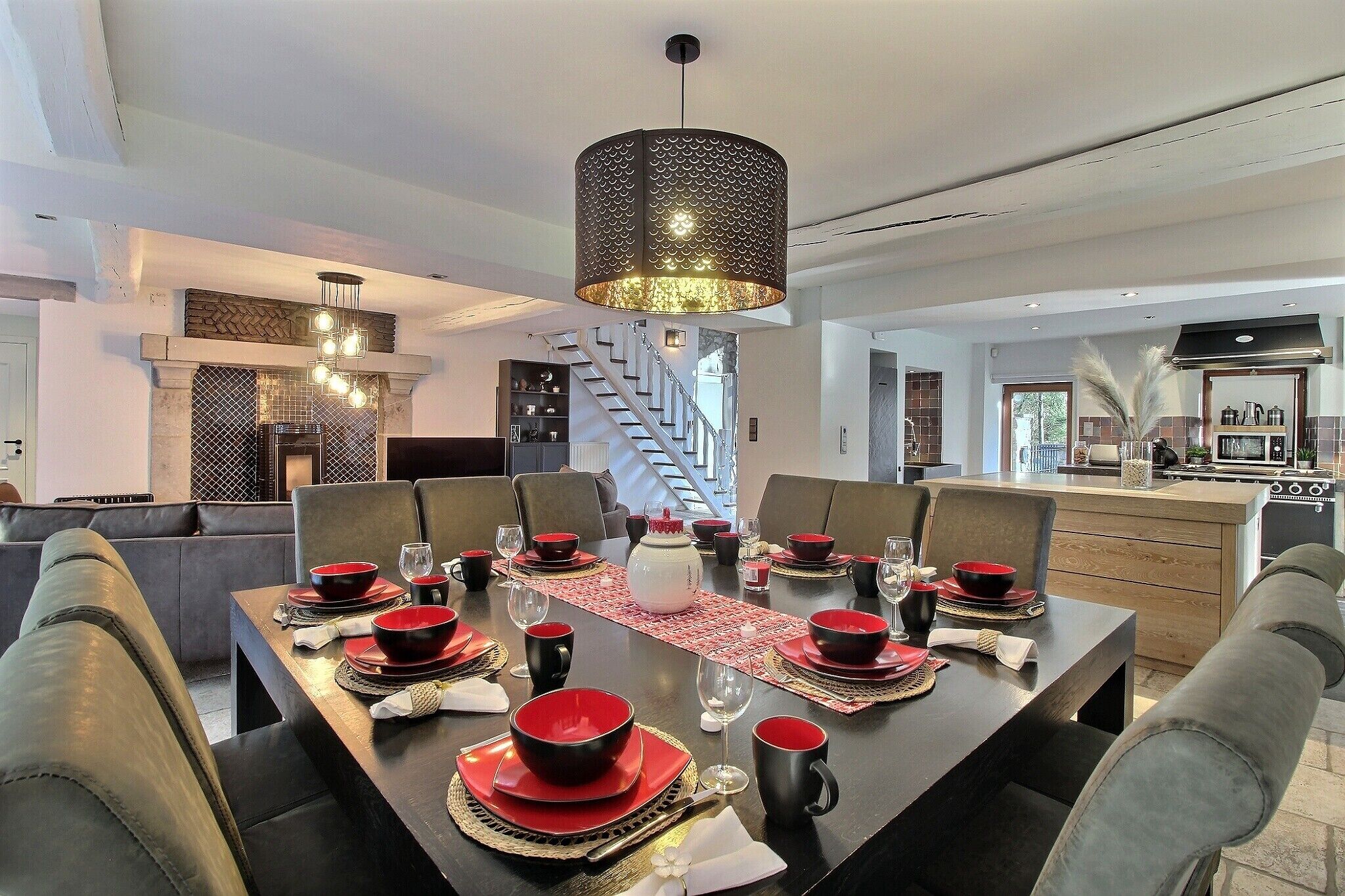 Un espace repas moderne avec une grande table rectangulaire dressée pour un repas, entourée de chaises grises à revêtement.