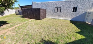 Un jardin avec un mur en pierre, une clôture en bois et un chemin dallé.