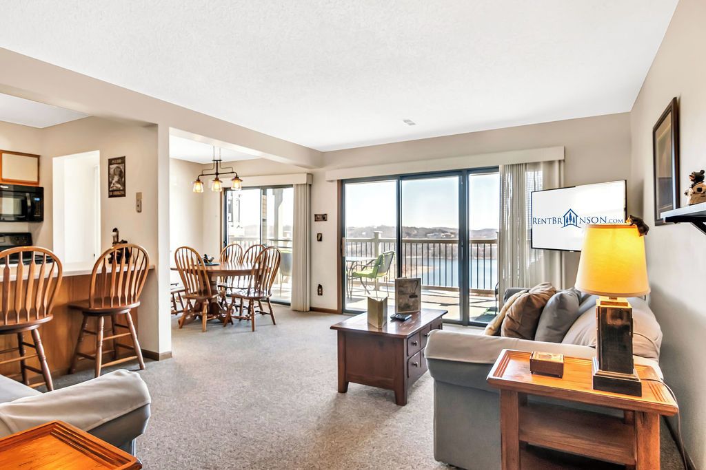 A spacious living room with a balcony, a dining area, and a kitchen.