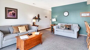 A living room with two sofas, a coffee table, a clock, and a framed picture on the wall. - Cozy Condo with Table Rock Lake Views, Free Tickets & 5 Minutes from Silver Dollar City (Branson)