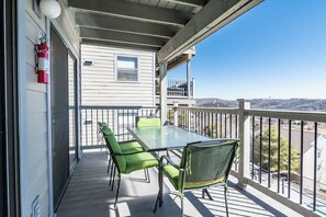 A balcony with a table and chairs, a fire extinguisher, and a view of the surrounding landscape.